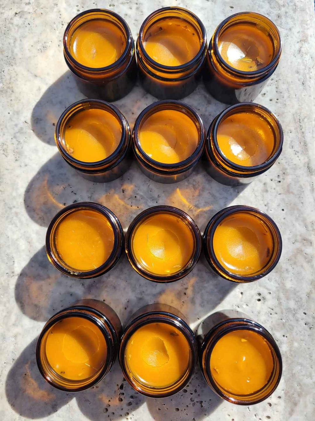 a group of amber jars sitting on marble filled with organic anti inflammatory salve