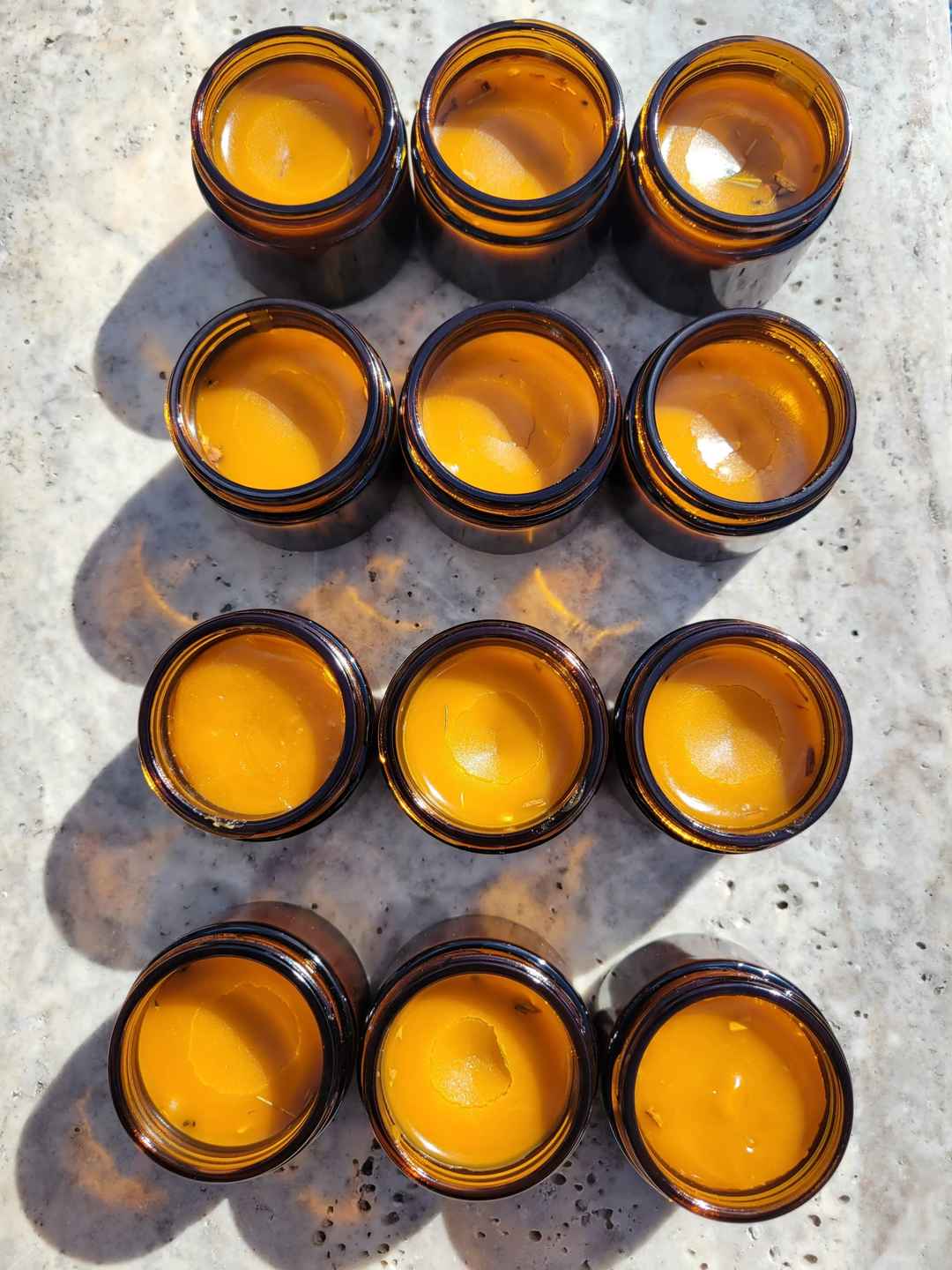 a group of amber jars sitting on marble filled with organic anti inflammatory salve