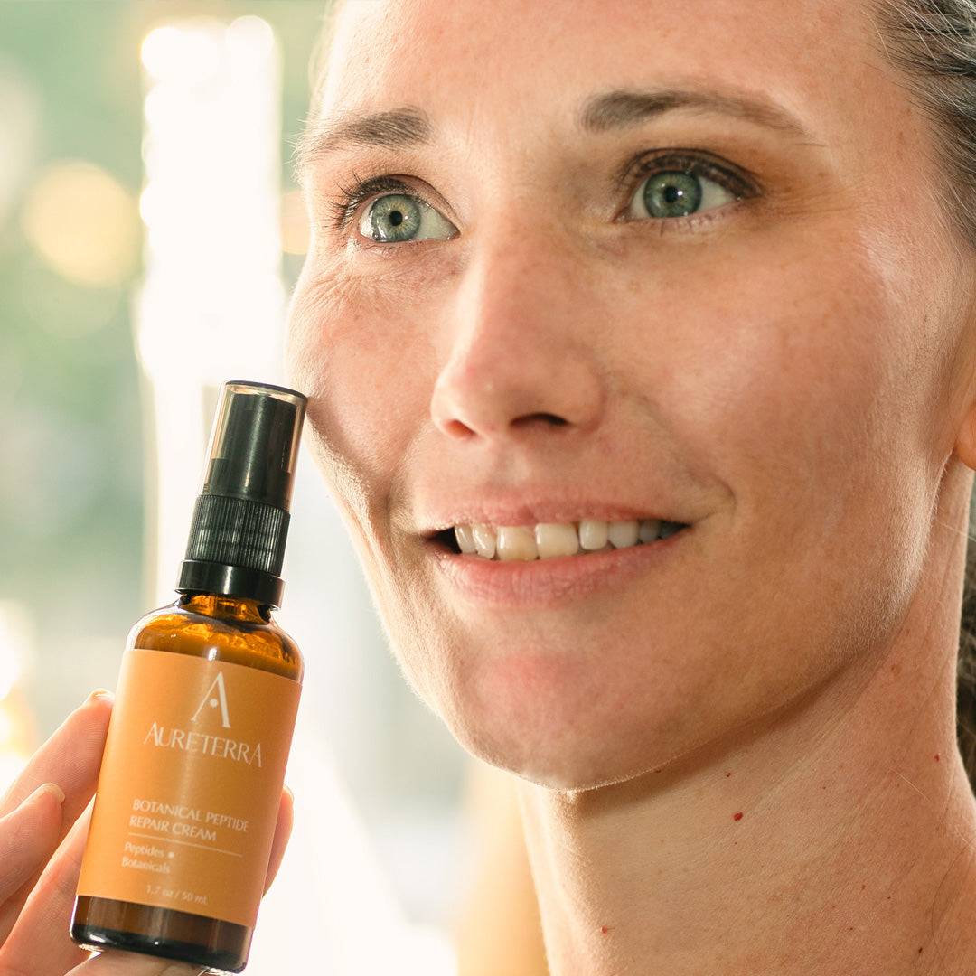 Person holding Aureterra Botanical Peptide Cream and smiling, showcasing natural skincare results and radiance.